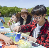 Group of people at a picnic table in Cadboro-Gyro Park having a picnic