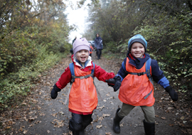 Two young children running down a trail while laughing