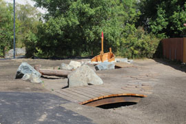 natural play area with wooden stepping blocks, ship, rocks and bridge